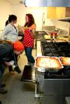 Joy Trimble, sophomore intercultural studies major, and Kelsey Nagy, sophomore art major, stand by to help with food preparations as the art department secretary, Angela McDaniel, checks the oven at the annual art retreat. - Photo by Kristi McMurry