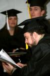 Ben Townsend, receiving his bachelor of science in computer science, reads his program while waiting for the fall commencement services to begin.  - Photo by Kristi McMurry