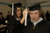Graduate Melanie Golden helps a fellow graduate adjust her cap before the ceremony begins. - Photo by Jim Veneman