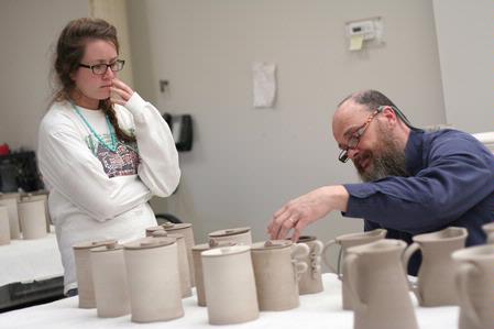 Lee Benson, professor of art and department chair, critiques Kelsey Nagy's canisters for Ceramics IV. 