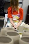Rachel Moore, junior art major, works on some pottery while pieces she has already made sit on the table in front of her.  - Photo by Ebbie Davis