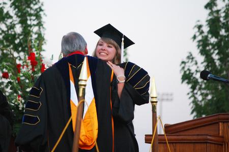 Betsy Davis, senior class president, embraces David S. Dockery, president of the university, before giving her speech at spring graduation.