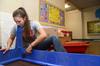 Kristi McMurry, web design specialist, assembles educational tables at Lloyd Wood Middle School for incoming Holt elementary students. After devastating tornadoes hit Tuscaloosa, water damage forced Holt elementary to move into the vacant school, which was scheduled for demolition.   - Photo by Beth Spain