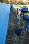 Freshmen nursing majors, Hannah Gerling and Rachel Massey, clear away grass on the football field at North Side High School during Campus and Community Day. - Photo by Ebbie Davis