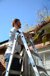 Luke Pruett, residence director, pulls down a rotted gutter during Campus and Community Day. - Photo by Ebbie Davis