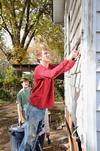 Stephen Hauss, sophomore business administration major, scrapes peeling paint off of a house during a service project with Sophomore Council. - Photo by Jacob Moore