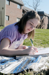 Junior Sarah Bradley enjoys the sunny spring weather while studying between the dorms. - Photo by Justin Veneman