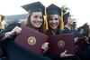 Social work graduates Courtney Allen and Courtney Burton excitedly hold up their diplomas during spring graduation.   - Photo by Anne Richoux