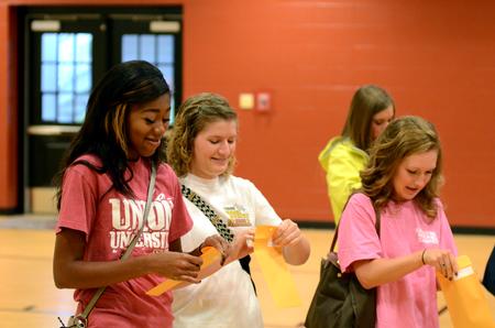 Holly Johnson, freshman business major, and other freshmen girls excitedly open their bid card envelopes to find out which sorority they will join on bid day.