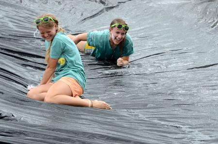 Seniors Elizabeth Cochran and Hillary Craft laugh as they go down the slip 'n slide during Panhellenic Bid Day.