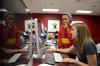Alesia Fisher, junior art major, looks over a news page of the Cardinal & Cream student newspaper with Amelia Krauss, senior journalism major. - Photo by Jacob Moore