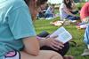 Holly Harris, junior nursing major, follows along as Virginia Walker reads from the book of Ephesians during Klemata Bible Study on the Great Lawn. - Photo by Olivia Wallace
