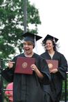 Krista Bradley, teaching English as a second language graduate, and Amanda Browning, family studies graduate, celebrate as they walk back to their seats after receiving their diplomas at Spring Graduation. - Photo by Anne Richoux