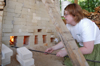 Junior Zandy Jackson, art major, stokes the fire on
the homemade wood kiln built by six university students on the back of Union’s property near Facilities Management. - Photo by Lindsay Stavish