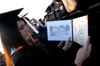 Digital media studies graduate Lauren Ormsby examines the layout of her degree at spring graduation. - Photo by Brad Moore
