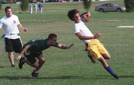 Freshman Joel Polk, narrowly escapes a tackle in the intramural flag football game by sophomore Logan Creasy, music major, while junior Chad Davis, Christian studies major, looks on.