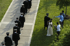 Graduates file onto the Great Lawn at the beginning of the graduation ceremony while one graduate jumps out to say hello to a friend. - Photo by Kathleen Murray