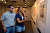 Seniors Jeff Reese & Stephanie Clark take a look at Adam Houston's work during his senior graphic design show in the Art Gallery. - Photo by Jonathan Blair