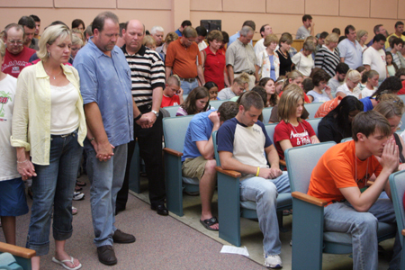 Parents surround their children in prayer at the worship service held on the first day of New Student Orientation. 