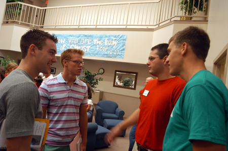 Enrollment Counselor Chad Cossiboom and Junior Chris Arnold talk with Freshmen Kirk Johnston and Mark Inman after they sign in at McAfee Commons on Freshman Move-In Day.
