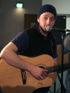 Enrollment Counselor Joe Garner plays his guitar and sings his original music at the Coffee House night for Rounders sign-ups, held Feb. 27 in the student lounge. - Photo by Kyle Kurlick
