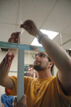 Aaron Hardin assists Alice Calvery in her art project that involves lowering the ceiling grid. - Photo by Brad Moore
