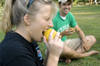 09/14/05 - Tori Gill takes a bite of a papaya for a game of Musical Fruit during a LIFE Group meeting as her leader Micah Whitaker watches. - Brad Moore
