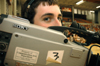 Aaron Hardin peeks over his camera while filming a basketball game. - Photo by Brad Moore