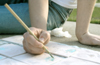 Junior Erin Laverty paints tiles outside the art department during finals week. - Photo by Heather Phillips
