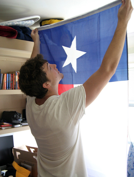 Peter Boedeker sets up his Texas flag while his parents help him unpack during freshman move-in day.