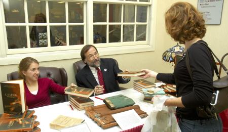 The Father-daughter team of Hal Poe, the Charles Colson Professor of Faith and Culture, and Junior Rebecca Whitten Poe, English major, sign copies of the book they edited <em>C.S. Lewis Remembered,</em> for Senior Melody Pickerill, Christian studies major.
