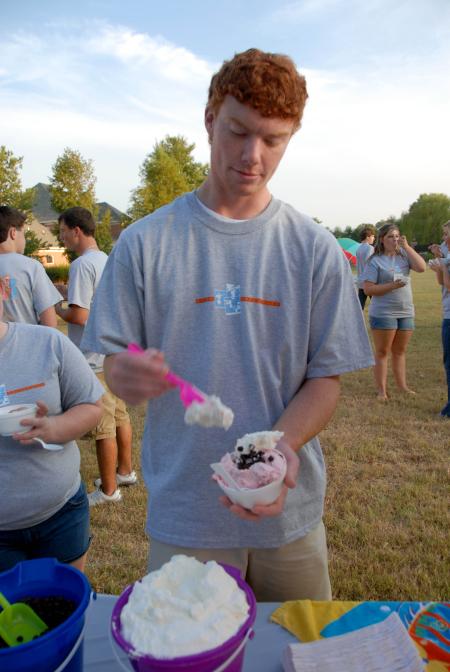 Tyler Jackson adds some whipped cream to his ice cream at the Ice Cream Social at President Dockery's home.