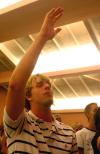 Sophomore Carter Collins raises his hand in praise as he sings along during the family chapel on the first day of orienation. - Photo by Stephanie Schroeder