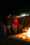 Sophomores Rebekah Frost and Paige Ward throw more wood into a pit fire.  Ceramics students were firing their projects primitive style. - Photo by Stephanie Schroeder