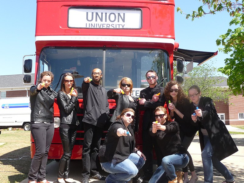 The Matrix characters take a few minutes to pose with the Red Bus Project bus, which serves to support orphans.