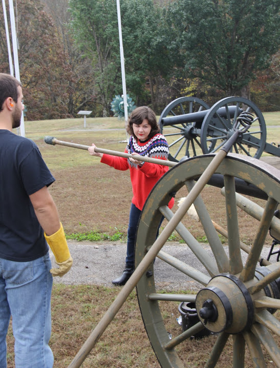 Priscilla Porter uses a rammer to push a packet of gunpowder into the barrel of a cannon as a step in readying it for firing on November 3, 2015. Allen Bradley watches her carry out her task.