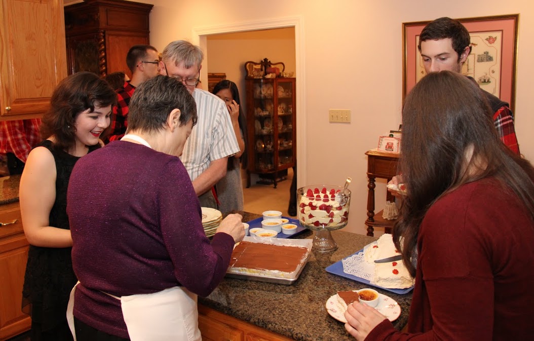 Attendees at the Phi Alpha Theta Christmas dinner on December 10, 2016, choose their desserts. In the foreground are (left to right, going clockwise) Priscilla Porter (wearing a black outfit) Dr. Terry Lindley, Luke Adkins, Jordan Sellers (back to camera), and Dr. Alice-Catherine Carls (back to camera), who is serving tiramisu.