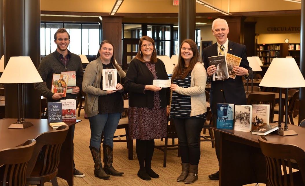 Delta-Psi Chapter President Jordan Sellers (second from right) presents a Phi Alpha Theta Best Chapter Award check to Library Director Melissa Moore on December 1, 2016. Delta-Psi chapter officers holding purchased history books are Secretary Seth Reid (left), Vice President Kathryn Mitchell (second from left), and Faculty Advisor Dr. Stephen Carls (right). Photo by Elizabeth Wilson