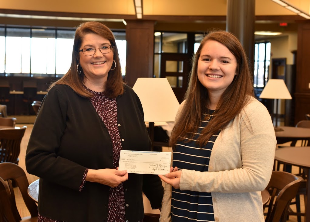 Delta-Psi Chapter President Jordan Sellers (right) presents a $250 Phi Alpha Theta Best Chapter Award check to Union University Library Director Melissa Moore on December 1, 2016. The Delta-Psi chapter purchased 12 history books for the library with the 2016 Best Chapter Award prize money. Photo by Elizabeth Wilson