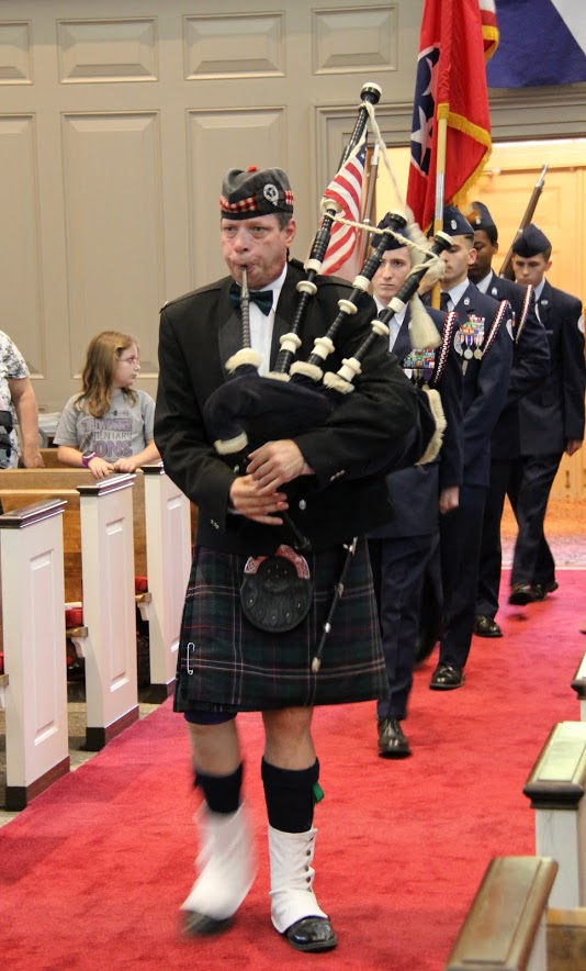 Bagpiper Dennis Dudley, followed by the Liberty Magnet High School Junior ROTC Color Guard, plays 