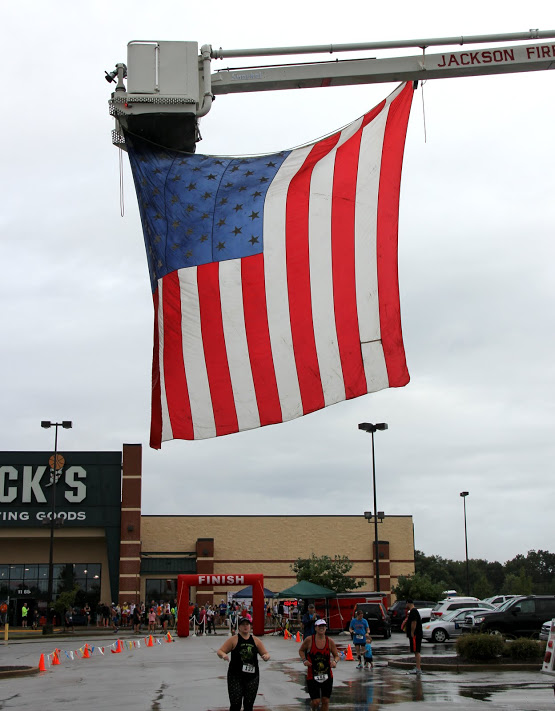 An American flag hangs from the cherry picker of a Jackson fire department truck to announce the start and finish lines of the Racing So They Can Ride event on September 17, 2016.