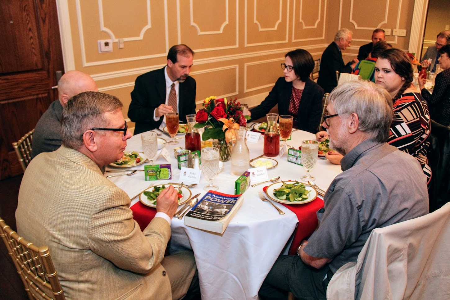 Attendees at the dinner in honor of Dr. Melvyn Leffler on October 22, 2018, engage in conversation and enjoy good food together. They are (starting on the front left and going clockwise) Dr. Ricky Garlitz, Dr. Greg Ryan (face obscured), Dr. Sean Evans, Lauren Butler, Jessica Barton, and Dr. Terry Lindley.