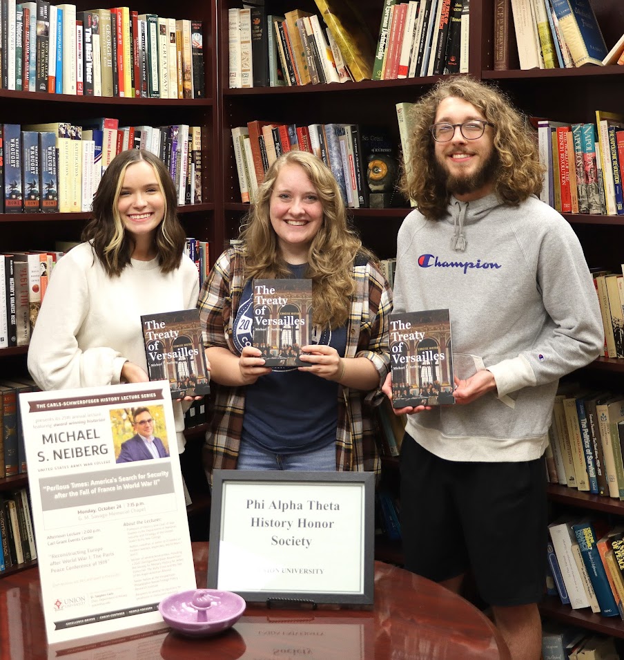 The three Phi Alpha Theta members who served as ushers at the evening lecture of the Carls-Schwerdfeger History Lectureship on October 24, 2022, hold autographed copies of a book by Dr. Michael Neiberg that they received for their service. The students are (left to right) Abbie Hobson, Breanna Edmiston, and Nicholas Palmer.