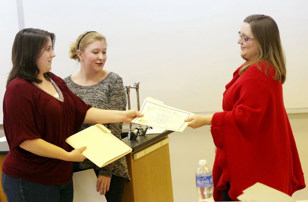 Delta-Psi Chapter President Faith Bagley (left) presents Hannah Conway (right) with her Phi Alpha Theta certificate of membership at the organization's spring initiation on February 24, 2015. Vice President Hannah Jones (center left) watches the ceremony.  Photo by Kristi Woody
