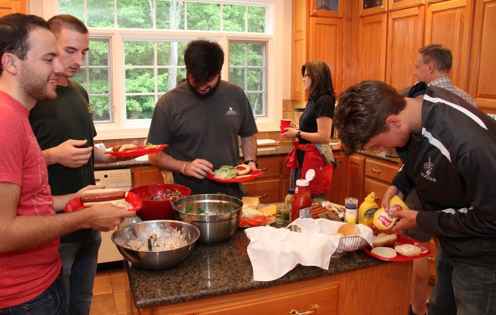 Attendees go through the food line at the 25th Annual Phi Alpha Theta/History Department Cookout at Dr. Carls's home on May 12, 2017. They are (front, left to right) Jeremy Ebert, Jeff Williams, Luke Parrett, and Stephen Lewoczko. In the background are Haelim Allen (center right) and Dr. Henry Allen (right, back to camera).