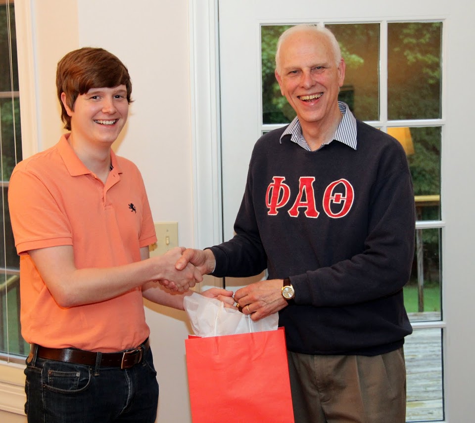 Thomas Gray accepts congratulations and a graduation award bag from Dr. Stephen Carls at the Phi Alpha Theta cookout on May 12, 2017.