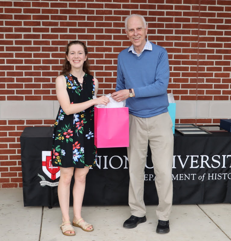 Graduating history major Anne Adams accepts a graduation gift award from Dr. Stephen Carls at the History Department Awards Program on April 28, 2022.