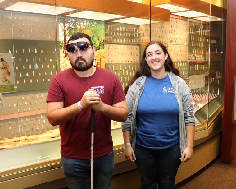 Phi Alpha Theta members Chris Young and Joy Brown stand in front of an arrowhead collection in the Native American Gallery at Discovery Park of America on April 1, 2023.