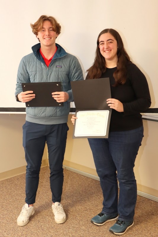 Joy Brown displays her Phi Alpha Theta membership certificate while standing with Delta-Psi President Tad Binkley at the chapter's spring plenary meeting on February 20, 2023.