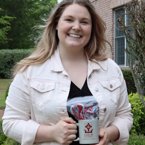 Graduating history major Alex Barger holds her history department coffee mug and Phi Alpha Theta honor cord during a presentation ceremony at Dr. Stephen Carls's home in May 2020.